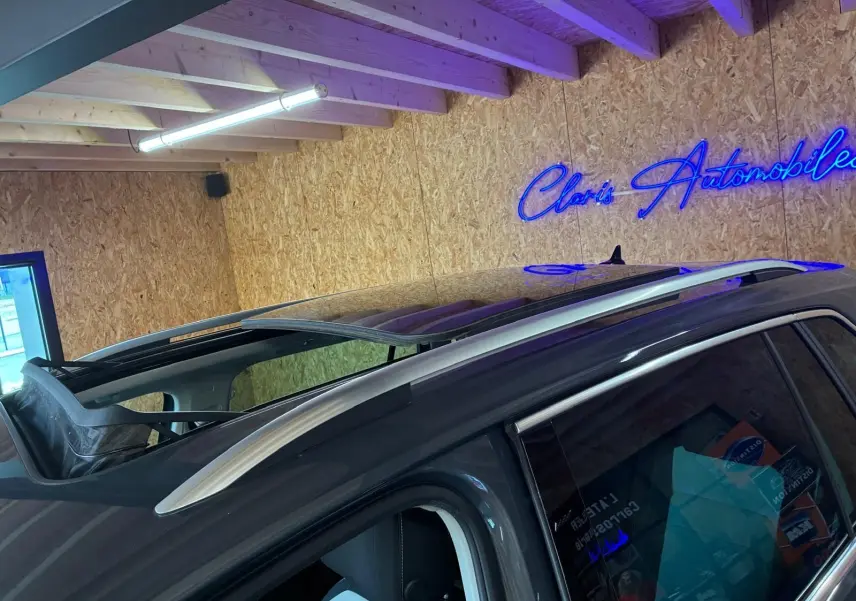 Vue rapprochée du toit ouvrant panoramique ouvert sur un Volkswagen Tiguan gris, angle côté gauche arrière.