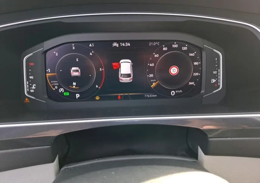 Vue rapprochée du tableau de bord digital du Volkswagen Tiguan 2023 affichant la vitesse, la température et l'alerte porte ouverte.