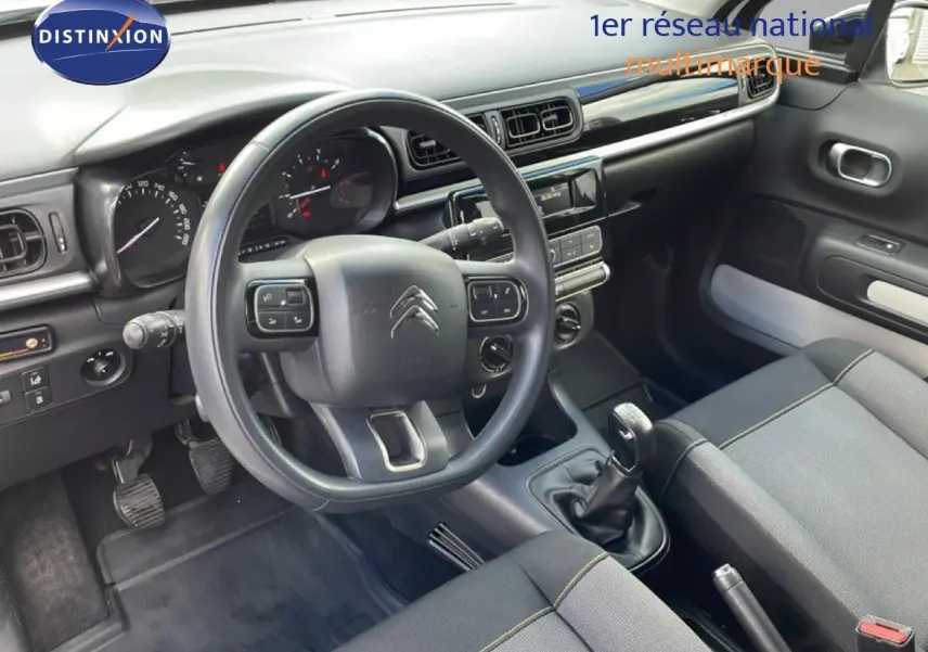 Vue intérieure côté conducteur de la Citroën C3 Société 2019, tableau de bord gris noir avec volant multifonctions.