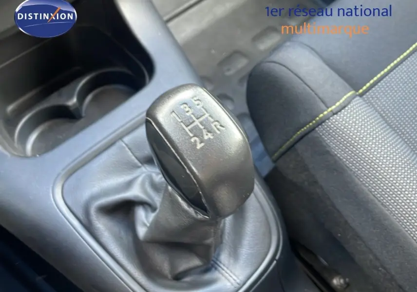 Gros plan sur le levier de vitesses manuel noir et la sellerie tissu gris avec surpiqûres jaunes d'une Citroën C3 blanche.
