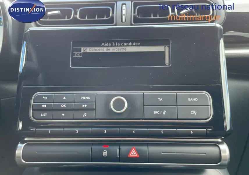 Vue rapprochée du tableau de bord noir de la Citroën C3 Société blanc banquise, avec écran d’aide à la conduite et commandes radio.