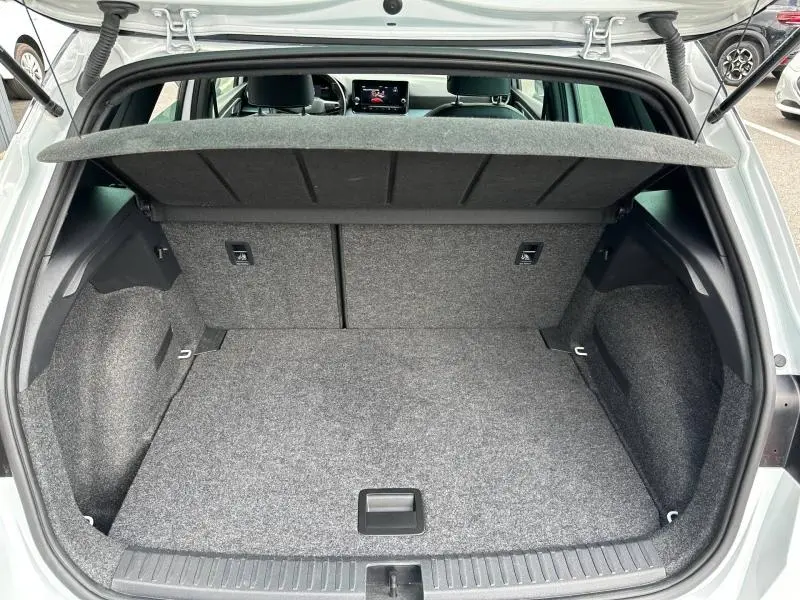 Coffre ouvert vu de l'arrière du SEAT Arona blanc Nevada, montrant un espace de chargement propre et tapis gris.