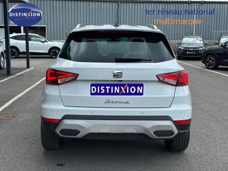 Vue arrière d'un SEAT Arona blanc Nevada avec toit noir, garé sur un parking extérieur.