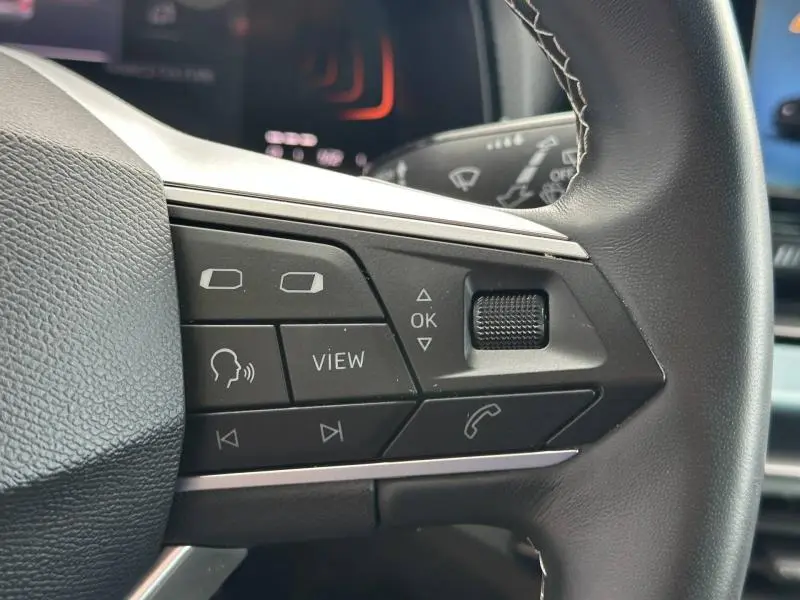 Gros plan sur les commandes multifonctions en cuir noir du volant du SEAT Arona 2025, côté gauche.