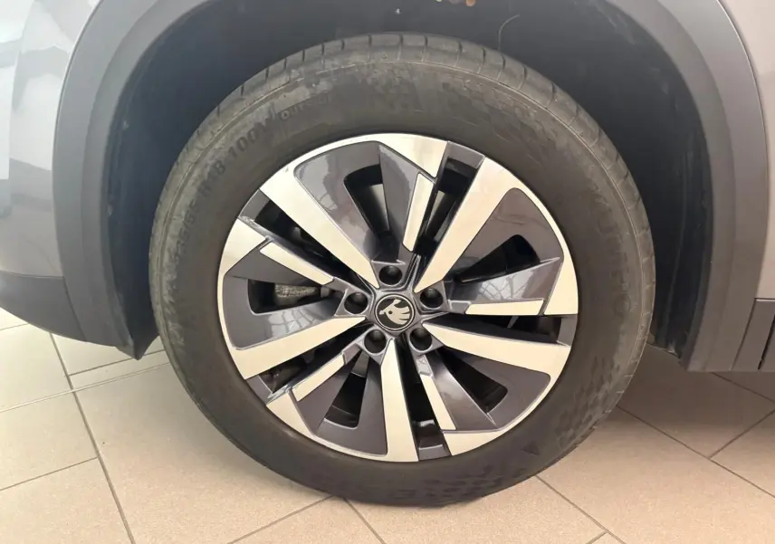 Gros plan sur la roue avant gauche d’un Skoda Kodiaq gris graphite, mettant en valeur la jante alliage bicolore.