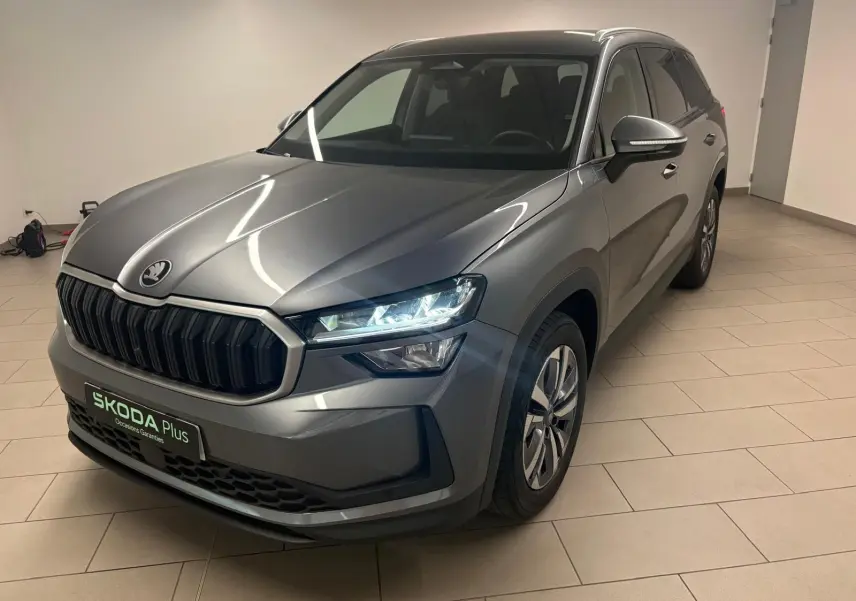 Vue 3/4 avant droit du Skoda Kodiaq 2025 gris graphite avec calandre noire et phares allumés en intérieur.