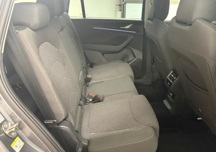 Vue intérieure côté gauche des sièges arrière gris foncé du Skoda Kodiaq 2025 avec éclairage d'ambiance violet sur la porte.