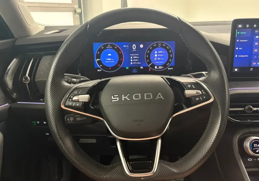 Vue intérieure centrée sur le volant perforé noir du Skoda Kodiaq 2025 avec tableau de bord numérique et écran tactile.