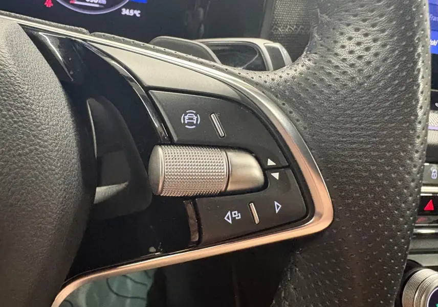 Gros plan sur les commandes au volant côté gauche du Skoda Kodiaq gris graphite 2025, avec molette texturée et boutons tactiles.