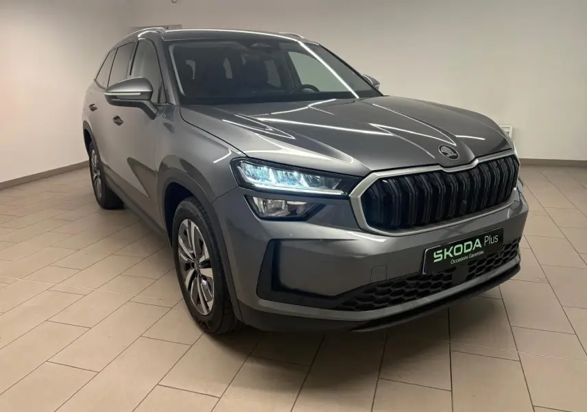 Vue 3/4 avant droite du Skoda Kodiaq gris graphite 2025 avec calandre noire et phares LED allumés.