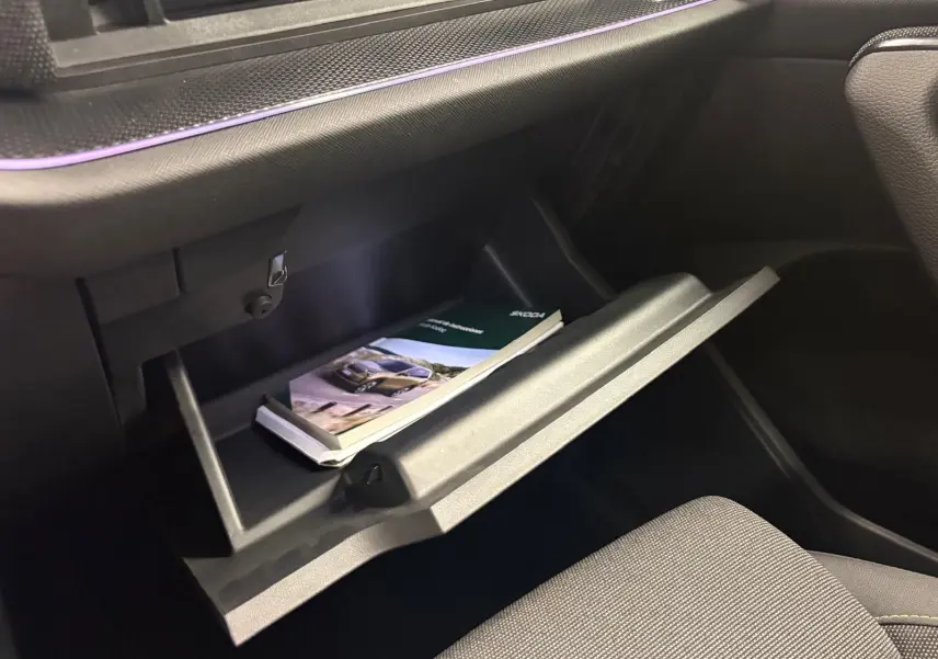 Gant de boîte ouvert côté passager du Skoda Kodiaq gris graphite 2025, avec manuel utilisateur visible à l'intérieur.