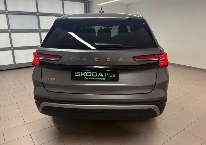 Vue arrière d’un Skoda Kodiaq gris graphite 2025 avec feux LED allumés dans un showroom intérieur.