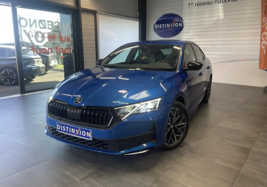 Skoda Octavia 2025 bleu foncé vue 3/4 avant en intérieur avec jantes alliage noires et calandre marquée.