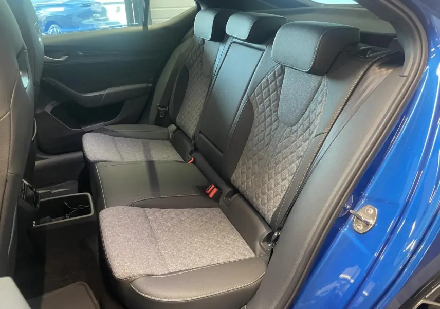 Vue intérieure côté droit sur la banquette arrière bi-matière grise et noire d’une Skoda Octavia bleu foncé 2025 Sportline.