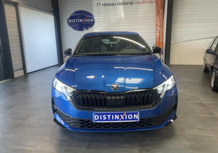 Vue avant d'une Skoda Octavia Sportline bleu foncé avec calandre noire et phares allumés en showroom.