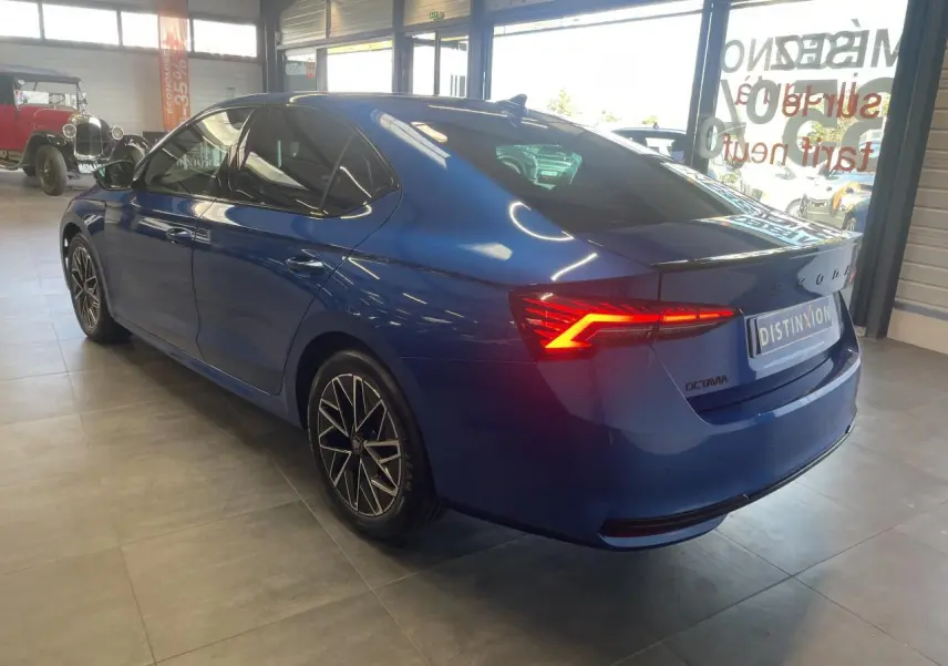 Vue 3/4 arrière droite d'une Skoda Octavia Sportline bleu foncé avec feux arrière LED et jantes alliage noires.