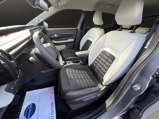 Vue intérieure côté conducteur de la Citroën C3 Aircross hybride 2025 avec sièges bicolores noir et blanc et volant cuir.