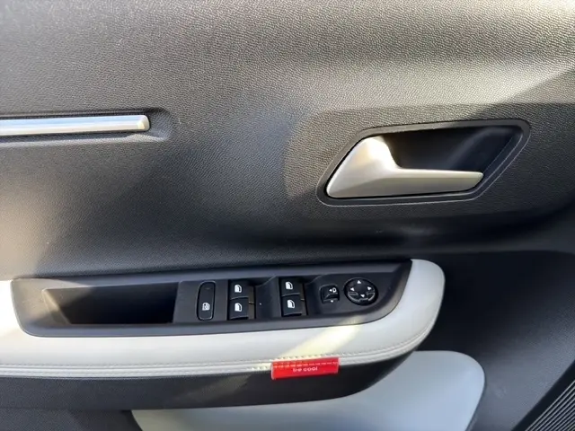 Gros plan sur la porte côté conducteur de la Citroën C3 Aircross hybride gris foncé, avec commandes électriques des vitres et poignée argentée.