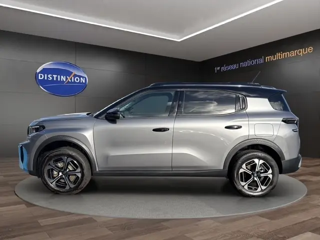 Profil droit d'un Citroën C3 Aircross hybride gris foncé avec jantes noires et toit noir en showroom.