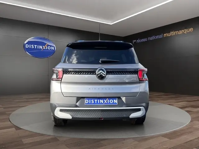 Vue arrière d'une Citroën C3 Aircross hybride gris foncé, avec feux LED et toit noir dans un showroom.