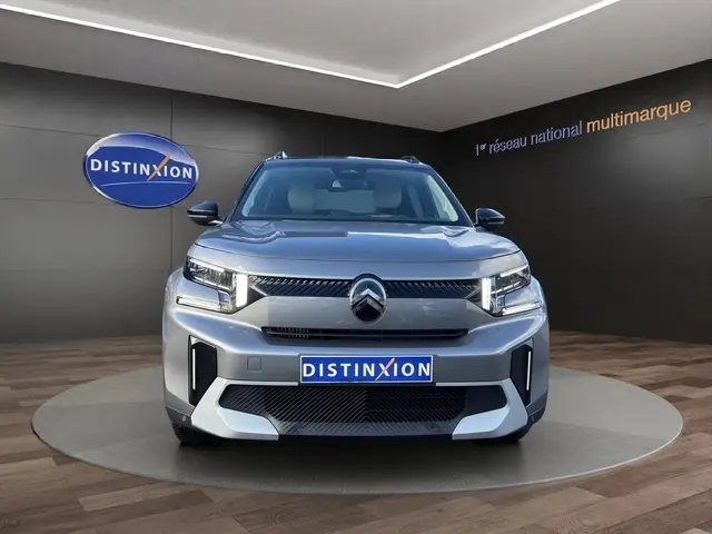Vue frontale d'un Citroën C3 Aircross hybride gris foncé avec feux LED et calandre distinctive en showroom.
