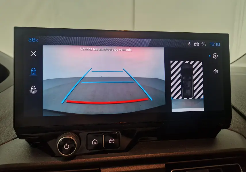 Écran intérieur du Peugeot Partner XL 2025 montrant la caméra de recul avec lignes de guidage colorées et vue aérienne du véhicule.