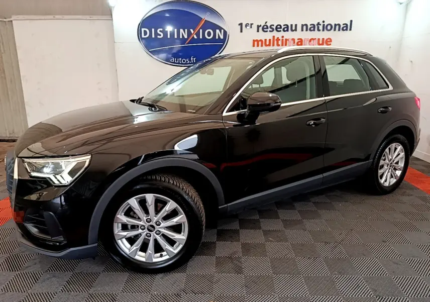 Audi Q3 noir vue de profil côté gauche dans un showroom avec jantes argentées et logo Distinxion en arrière-plan.