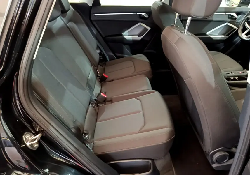 Vue intérieure côté gauche sur la banquette arrière noire de l’Audi Q3 35 TDI 2021 avec sièges tissu et appuie-têtes réglables.