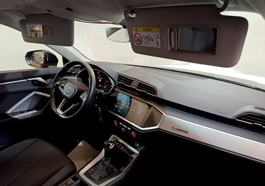 Intérieur Audi Q3 35 TDI 2021 vu côté conducteur, tableau de bord moderne avec écran tactile et volant cuir noir.