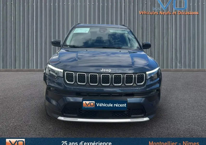 Vue frontale d'un Jeep Compass bleu 2023 avec calandre distinctive et phares à LED allumés.