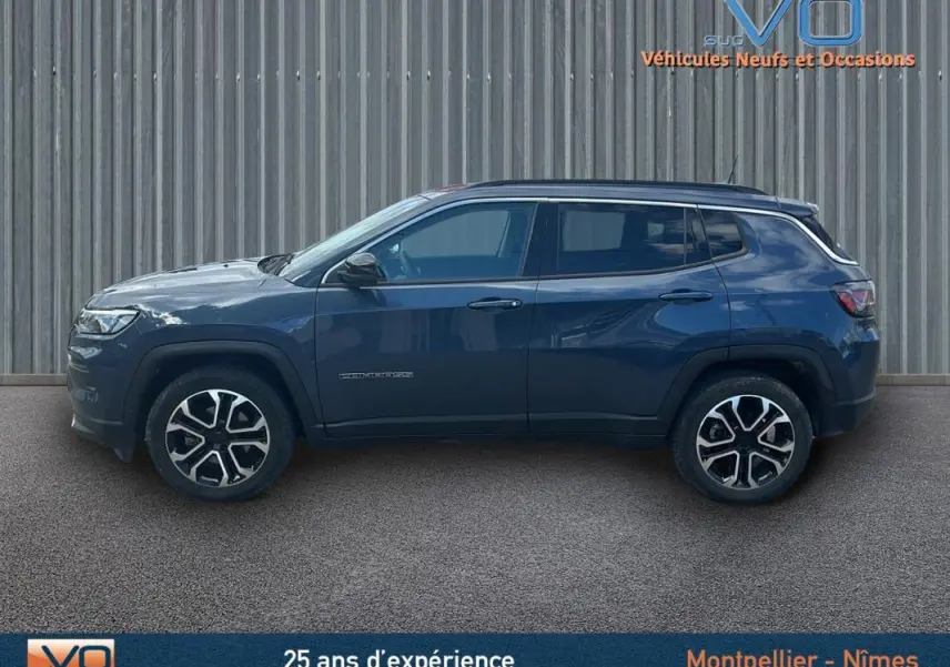 Vue latérale droite d'un Jeep Compass bleu 2023 avec jantes 18 pouces et barres de toit, sur fond neutre.