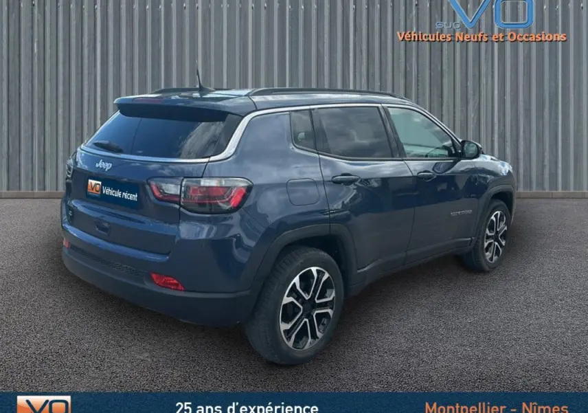 Vue 3/4 arrière droite d’un Jeep Compass bleu 2023 avec barres de toit et jantes 18 pouces distinctives.