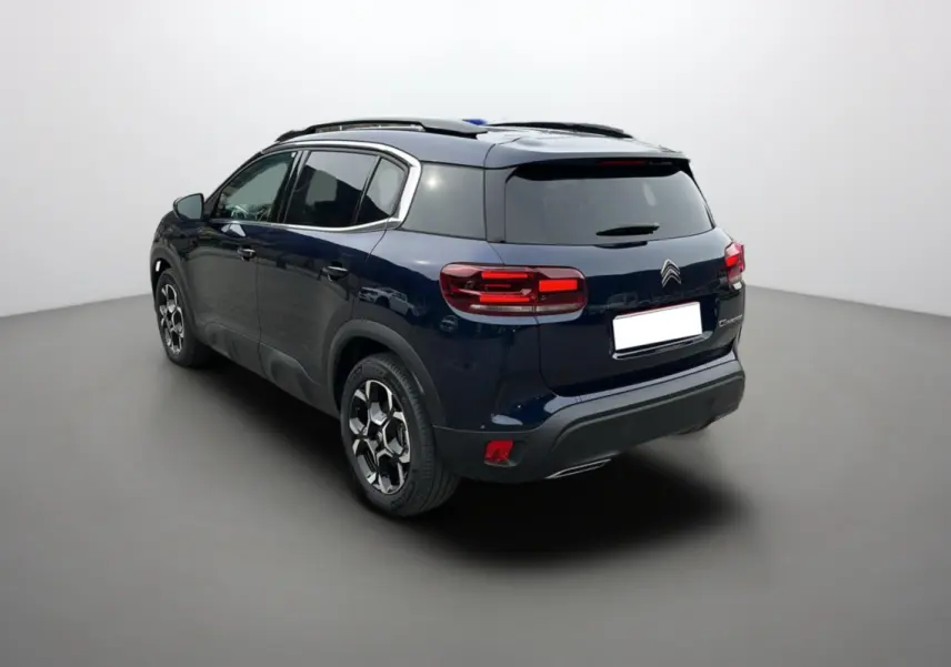 Vue 3/4 arrière gauche du Citroën C5 Aircross Hybrid 145 en Eclipse Blue avec barres de toit et jantes alu 18 pouces.