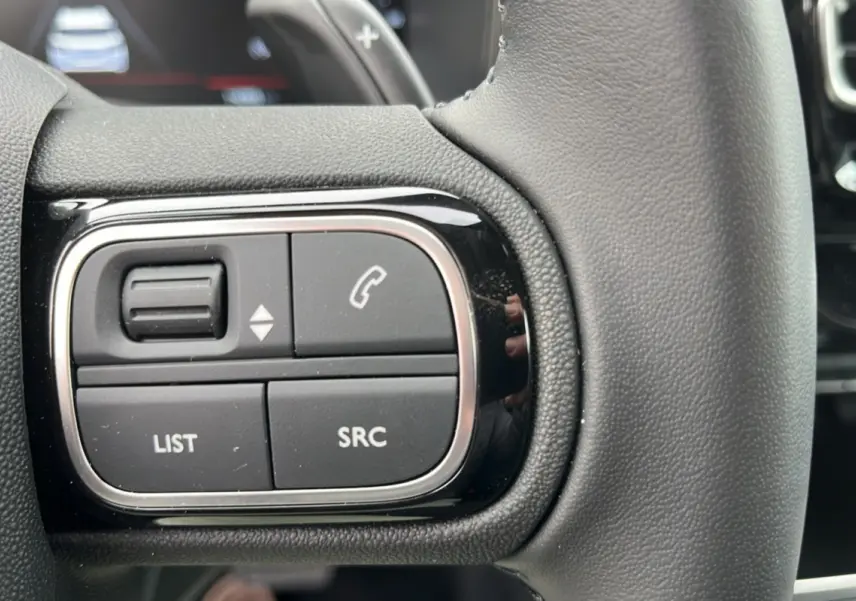 Gros plan sur les commandes gauche du volant cuir multifonctions du Citroën C5 Aircross Hybrid 145 en noir.