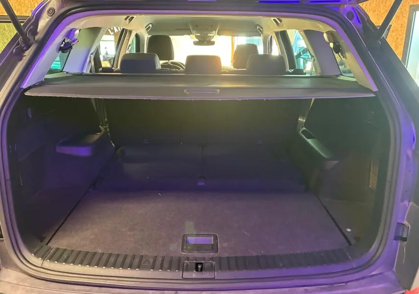 Vue arrière du coffre ouvert d'un SKODA KODIAQ gris 7 places, avec cache-bagages et sièges arrière visibles.
