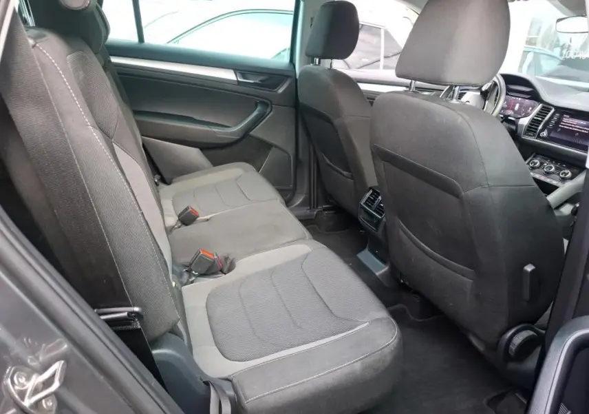 Vue intérieure côté gauche du Skoda Kodiaq 2023, sièges tissu gris et tableau de bord visible à l'avant.