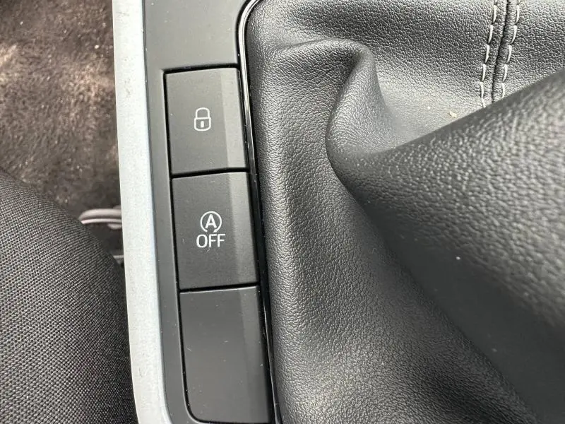 Gros plan sur les boutons de commande et soufflet de levier de vitesse en cuir noir dans la SEAT Arona 2025.