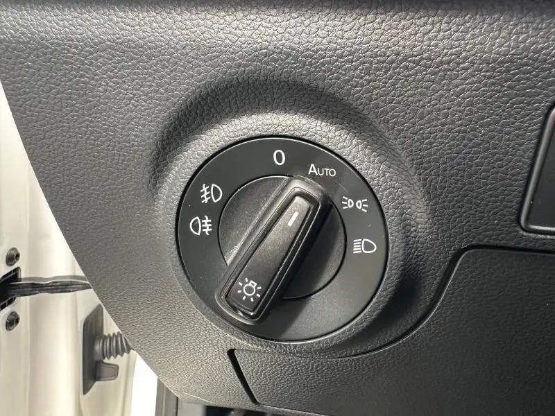 Gros plan sur le bouton de commande des phares du tableau de bord d'une SEAT Arona blanc Candy 2025.