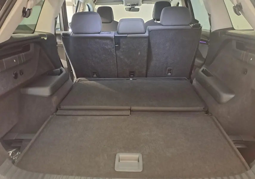 Vue depuis le coffre du Skoda Kodiaq gris graphite 2025, montrant l'espace de chargement et les sièges arrière en position relevée.
