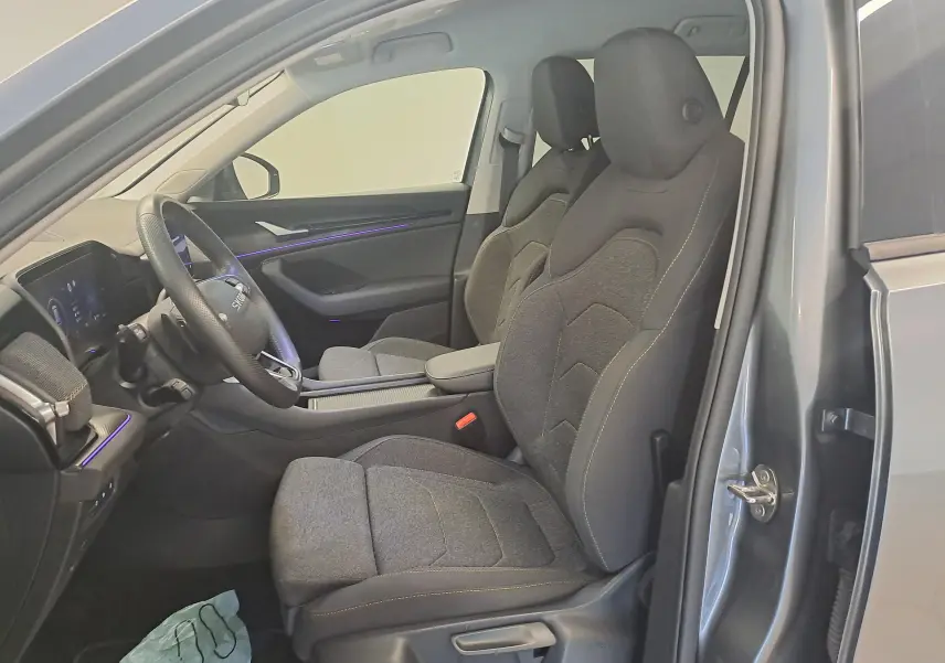 Vue intérieure côté conducteur du Skoda Kodiaq gris graphite 2025, mettant en valeur les sièges tissu et le tableau de bord moderne.