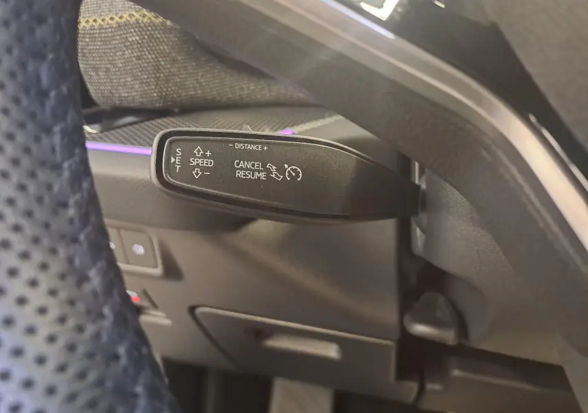 Gros plan sur la commande de régulateur de vitesse du Skoda Kodiaq 2025, intérieur noir avec éclairage d’ambiance violet.