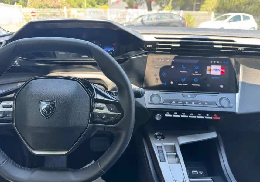 Intérieur Peugeot 308 2025 vu du conducteur, volant compact, écran tactile central et commandes modernes visibles.
