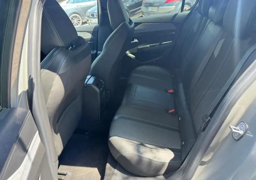 Vue intérieure arrière droite de la Peugeot 308 gris, montrant les sièges en tissu et cuir avec ceinture de sécurité rouge.