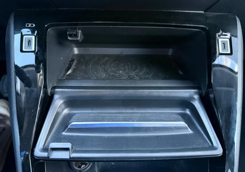 Vue rapprochée de la console centrale noire du Peugeot 208 Hybrid 110 e-DCS6 Allure avec ports USB et espace de rangement.