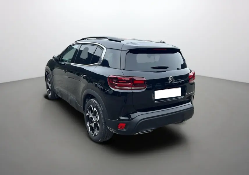 Vue 3/4 arrière droite d'un Citroën C5 Aircross Hybrid noir avec barres de toit et vitres surteintées.