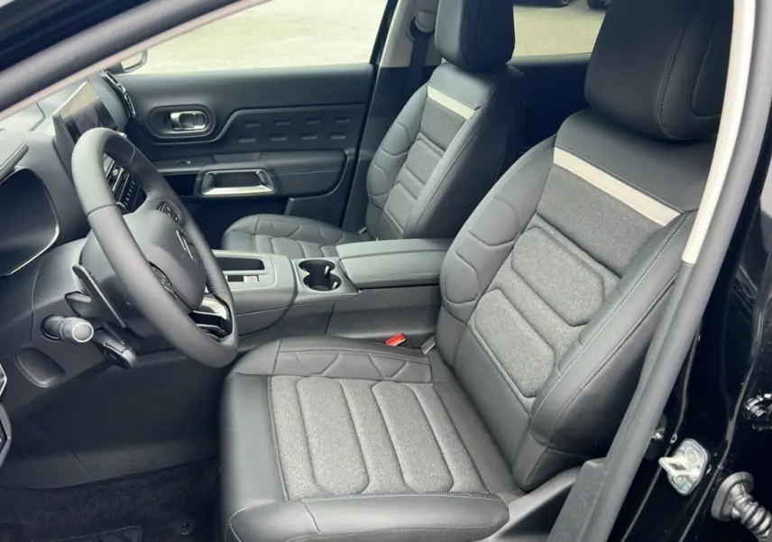 Intérieur avant du Citroën C5 Aircross Hybrid noir 2025, sièges tissu et cuir gris, volant multifonctions visible côté gauche.