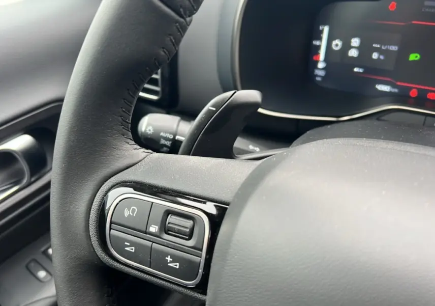 Gros plan sur le volant cuir noir du Citroën C5 Aircross Hybrid 145, avec commandes multifonctions et palettes au volant visibles.