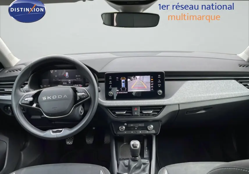 Vue intérieure avant du Skoda Scala blanc glacier 2025, avec tableau de bord moderne et écran tactile central allumé.
