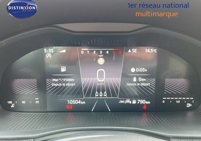 Vue rapprochée du tableau de bord numérique du Skoda Scala blanc glacier, affichant la vitesse à 0 km/h et 10 504 km au compteur.