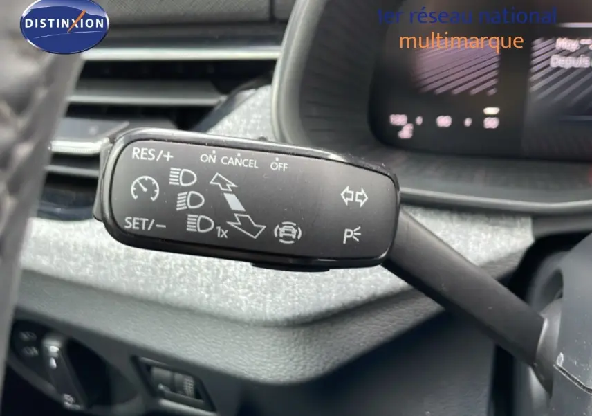 Gros plan sur la commande de régulateur de vitesse au volant d’une Skoda Scala blanc glacier 2025, intérieur gris noir.